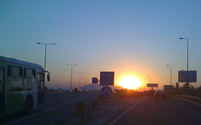 Cars on road against sky during sunset