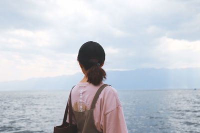 Rear view of man looking at sea against sky