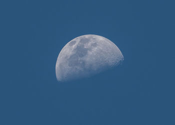 Low angle view of half moon against clear blue sky