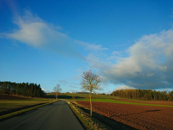 Road amidst field against sky