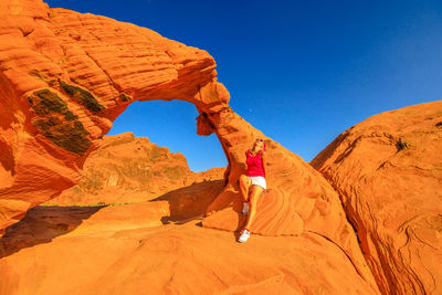 Man standing on rock formation against clear sky