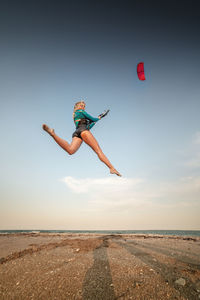 Sportswoman kitesurfer jumps with her kite on the beach. free flight over land with a kite