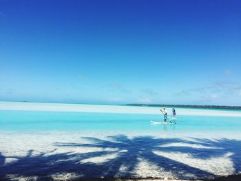 People on beach against clear blue sky