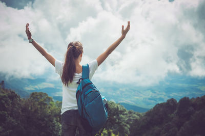 Rear view of woman with arms raised against sky