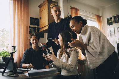 Young couple holding smart phone while standing at home