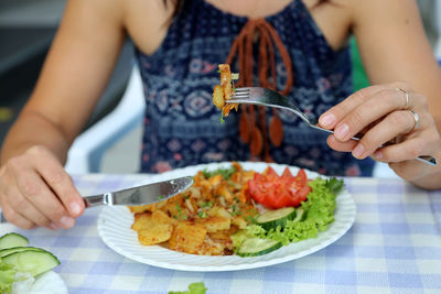 Midsection of woman eating food at table