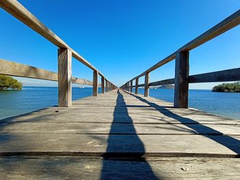 Bridge over calm blue sea against clear sky