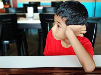 Close-up of thoughtful boy looking away while sitting at table