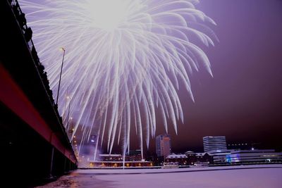 Firework display in city against sky at night