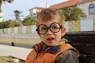 A blond boy in children's toy glasses looks into the distance in surprise. a comical   boy.