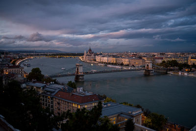 Szechenyi chain bridge over danube river in city at dusk