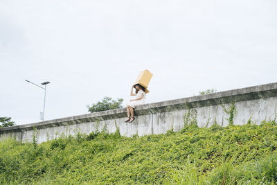 Woman standing by wall against sky