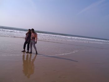 Full length of couple on beach against sky