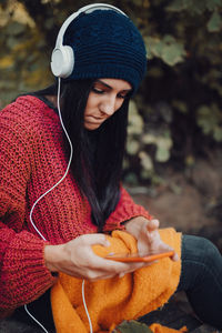 Beautiful woman wearing knit hat listening music in smart phone