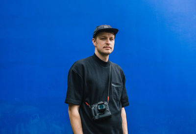 Portrait of young man standing against blue sky