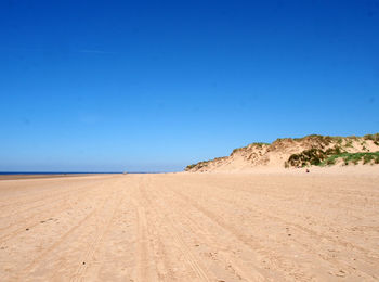 Scenic view of beach against clear blue sky