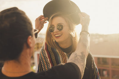 Rear view of man putting hat on happy girlfriend head