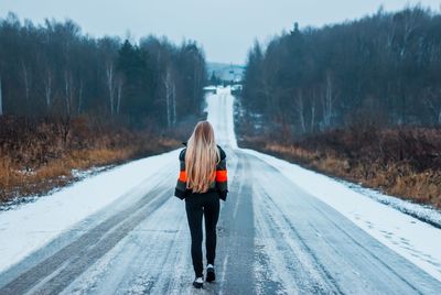 Rear view of woman on snow covered road