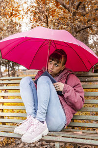Full length of woman sitting on wet umbrella