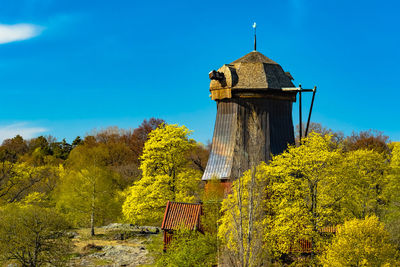 Yellow tower amidst trees and building against sky