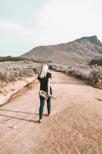 Full length rear view of woman on arid landscape