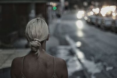 Rear view of woman standing on road at night