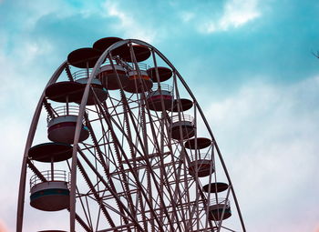 Low angle view of ferris wheel against cloudy sky