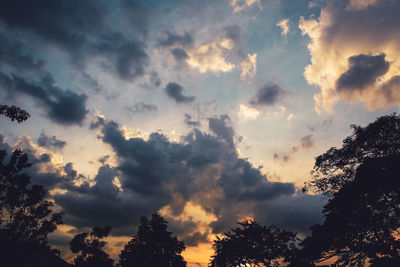 Low angle view of silhouette trees against dramatic sky