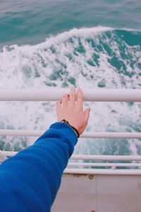 Cropped hand touching railing at boat deck