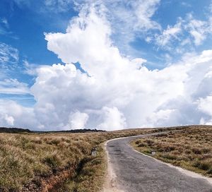 Road amidst field against sky