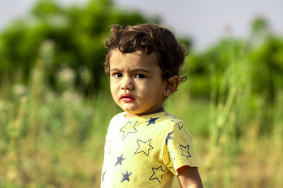 A sad little indian child angrily looking at the camera, asian kids in nature