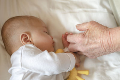 Cropped wrinkled hand touching baby at home