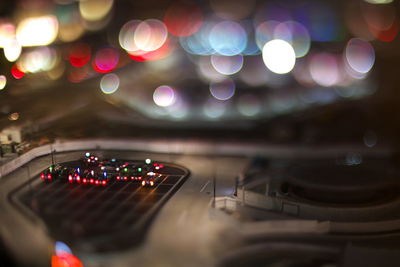 Tilt-shift image of illuminated taxis in parking lot below defocused lights at night