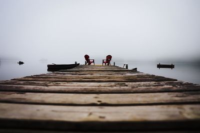 Surface level of pier over lake against sky during foggy weather