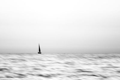 Sailboat sailing in sea against clear sky