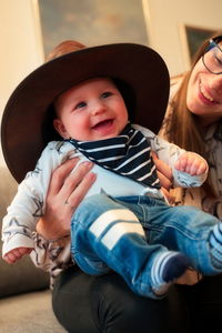 Portrait of cute little baby in cowboy hat holding by his mother