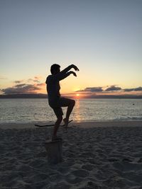 Silhouette man standing on beach against sky during sunset