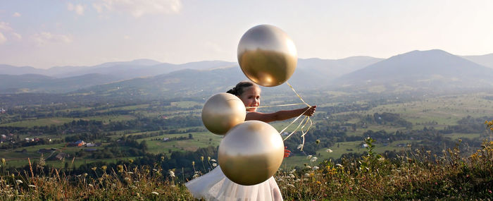 View of balloons on field against mountain range