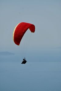 Low angle view of person paragliding in sea against sky