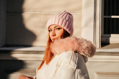 Portrait of young woman wearing knit hat standing outdoors