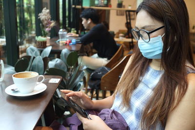 Midsection of woman holding coffee while sitting on table at cafe