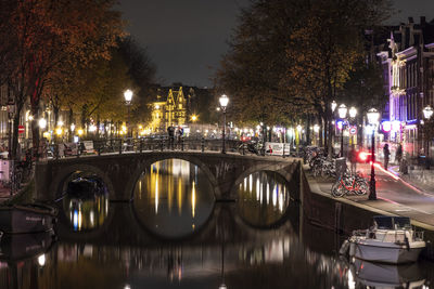 Illuminated bridge over canal in city at night
