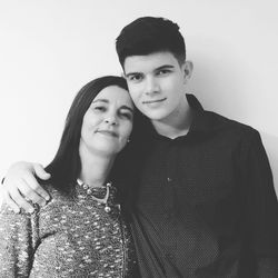 Portrait of smiling mother and son against wall