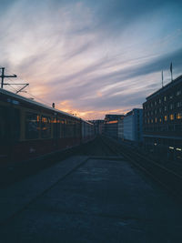 Train by buildings against sky during sunset