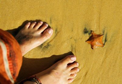 Low section of woman standing on sand