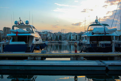 Boats at harbor against sky during sunset in city