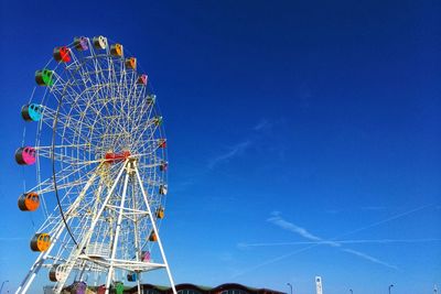 Low angle view of ferris wheel against clear blue sky