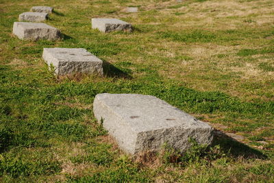 Stone wall by rocks on field