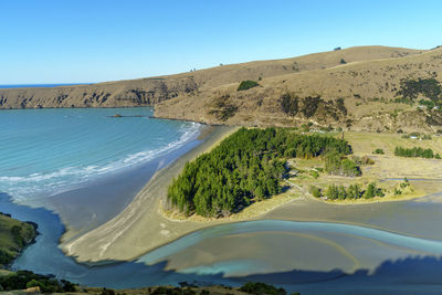 Scenic view of sea and mountains against clear blue sky