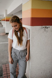 Young woman standing against wall